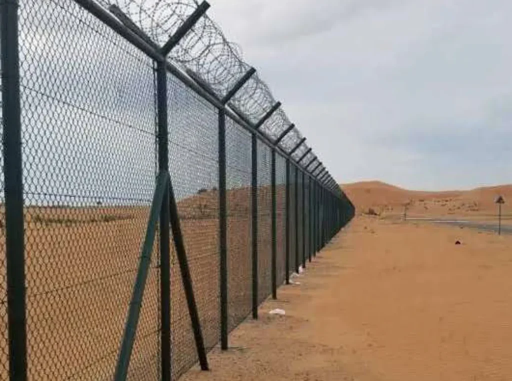 Security fencing with barbed wire along the labor camp perimeter in Mussafah